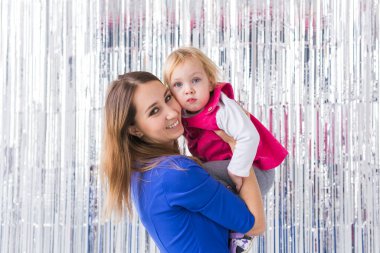 Çocukluk, sevgi ve aile kavramı. Anne bebeğini parlak arka planda tutuyor. Yakın plan.