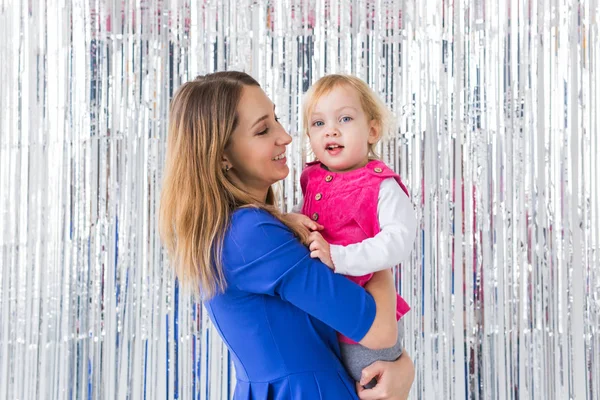 Infância, amor e conceito de família - A mãe mantém a filha bebê em fundo brilhante. Close-up — Fotografia de Stock