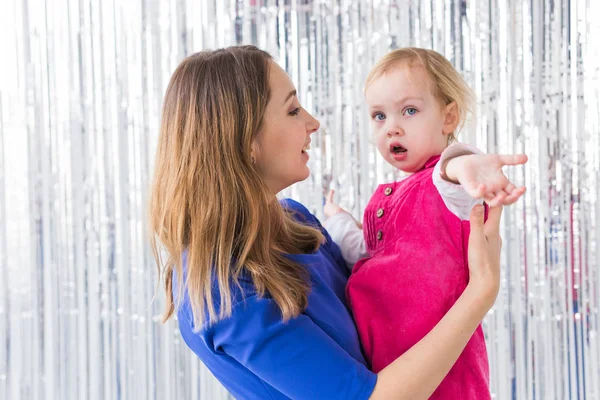 Jeugd, liefde en gezin concept - Moeder houdt baby dochter op glanzende achtergrond. Close-up — Stockfoto