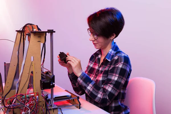 Concepto de tecnología e ingeniería: ingeniero femenino que trabaja en el laboratorio, está ajustando los componentes de una impresora 3D . — Foto de Stock