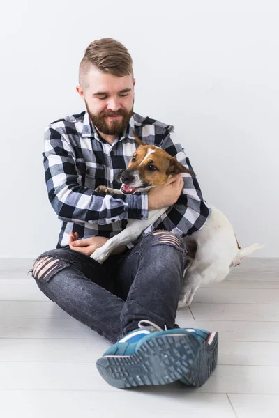 Domácí mazlíčci majitelé koncept - Atraktivní veselý pes v kostkované košili drží oblíbeného mazlíčka. Šťastný vousatý muž se svým Jack Russell teriérem — Stock fotografie