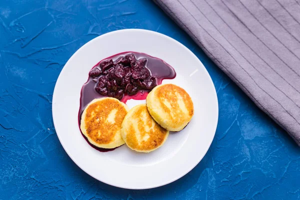 Завтрак и вкусная концепция - Блинчики из творога с джемом, синий фон . — стоковое фото