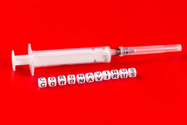 Pandemic and virus concept - Coronavirus text with syringe on red background. Novel coronavirus Covid-19. — Stock Photo, Image