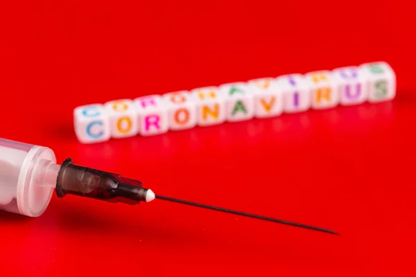 Concepto de pandemia y virus: texto y jeringa del coronavirus sobre fondo rojo. Nuevo coronavirus Covid-19 . —  Fotos de Stock