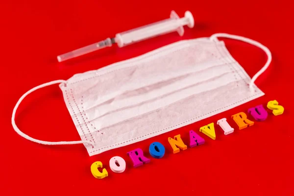 Palabra de Coronavirus hecha de letras de colores sobre fondo rojo. La inscripción en la máscara protectora médica coronavirus . —  Fotos de Stock