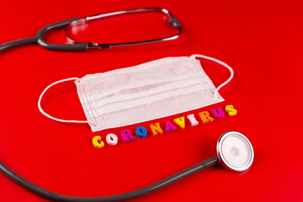 Palabra de Coronavirus hecha de letras de colores sobre fondo rojo. La inscripción en la máscara protectora médica coronavirus . —  Fotos de Stock