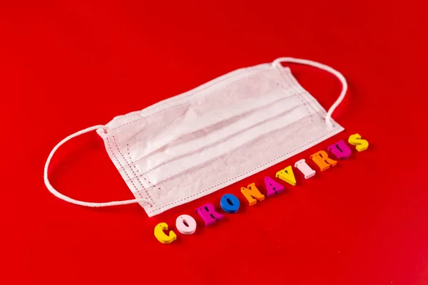 Coronavirus mot composé de lettres colorées sur fond rouge. L'inscription sur le masque de protection médicale coronavirus . — Photo