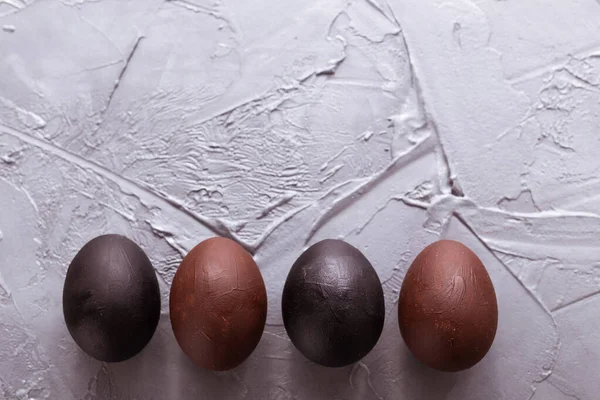 Holidays, design and modern easter concept - Black and brown easter eggs style minimalism on grey background with copy space.