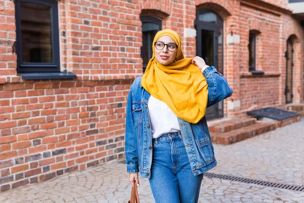 Vacker arabisk muslimsk student kvinna bär gul hijab, elegant kvinnlig porträtt över stadens gata. — Stockfoto