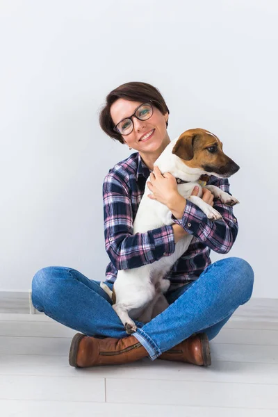 Pets owner concept - Attractive cheerful female in plaid shirt holds favourite pet. Happy woman with her jack russell terrier — Stock Photo, Image