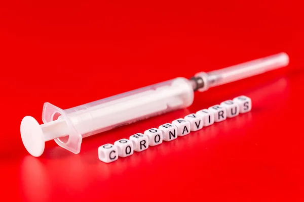 Concepto de pandemia y virus: texto del coronavirus con jeringa sobre fondo rojo. Nuevo coronavirus Covid-19 . —  Fotos de Stock