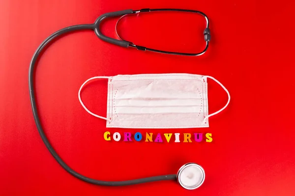 Palabra de Coronavirus hecha de letras de colores sobre fondo rojo. La inscripción en la máscara protectora médica coronavirus . —  Fotos de Stock