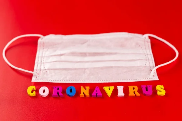 Coronavirus mot composé de lettres colorées sur fond rouge. L'inscription sur le masque de protection médicale coronavirus . — Photo