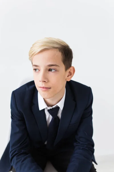 Portret van stijlvolle schooljongen tiener in wit shirt en jas tegen witte achtergrond. — Stockfoto