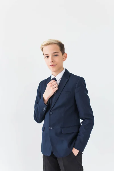 Portret van stijlvolle schooljongen tiener in wit shirt en jas tegen witte achtergrond. — Stockfoto