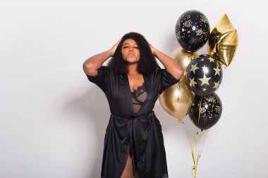 Tatiller, parti ve eğlence konsepti - Beyaz arka planda balonlarla şık görünen gülümseyen Afro-Amerikalı genç bir kadının portresi.
