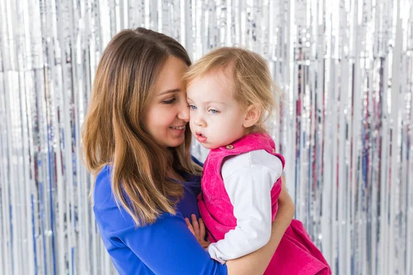 Infância, amor e conceito de família - A mãe mantém a filha bebê em fundo brilhante. Close-up — Fotografia de Stock