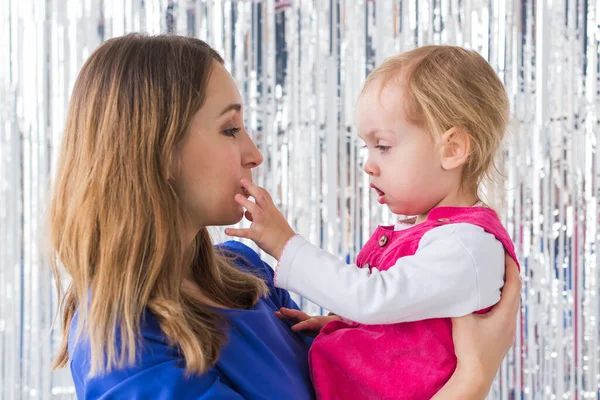 Jeugd, liefde en gezin concept - Moeder houdt baby dochter op glanzende achtergrond. Close-up — Stockfoto