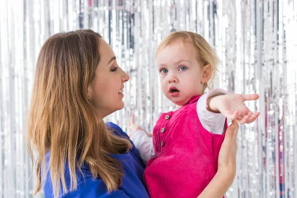 Infância, amor e conceito de família - A mãe mantém a filha bebê feliz em fundo brilhante. Close-up — Fotografia de Stock