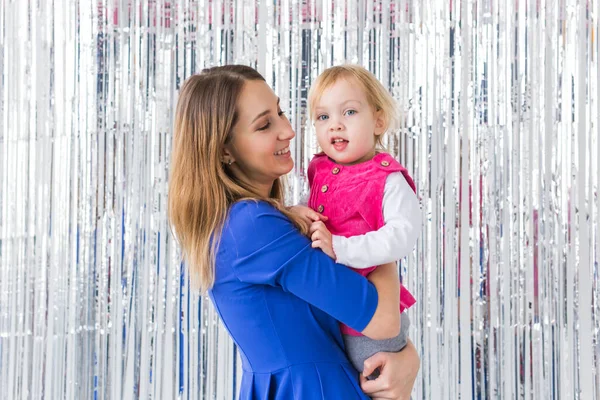 Jeugd, liefde en gezin concept - Moeder houdt gelukkige baby dochter op glanzende achtergrond. Close-up — Stockfoto