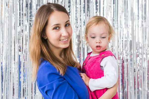 Jeugd, liefde en gezin concept - Moeder houdt gelukkige baby dochter op glanzende achtergrond. Close-up — Stockfoto