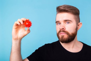 Covid-19, aşı geliştirme ve ilaç konsepti - Grip maskeli bir adam ve koruyucu eldivenli bir Coronavirus modeli.