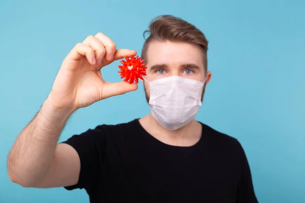 Covid-19, Ανάπτυξη εμβολίου και ιατρική έννοια - Man in flu mask and protective gloves holding a model of coronavirus. — Φωτογραφία Αρχείου