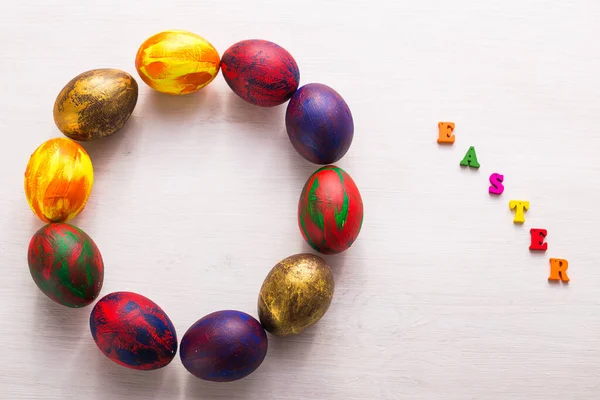 Letras de madera multicolores que componen las palabras feliz Pascua y huevos coloridos decorativos sobre un fondo blanco con espacio para copiar . —  Fotos de Stock