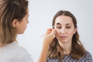 Güzellik ve kozmetik konsepti - Makyaj sanatçısı genç bir kadından profesyonel makyaj yapıyor