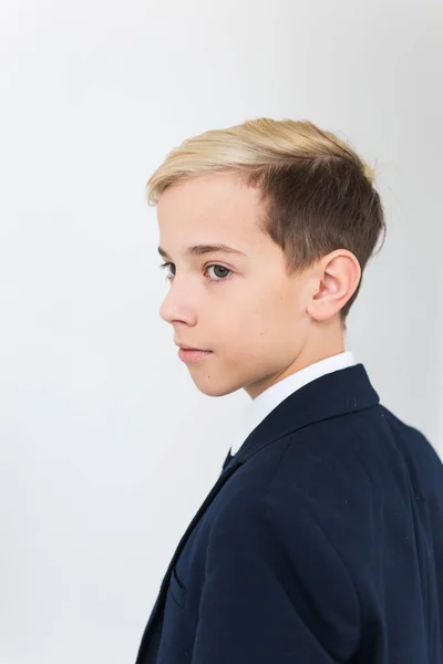 Portret van stijlvolle schooljongen tiener in wit shirt en jas tegen witte achtergrond. — Stockfoto
