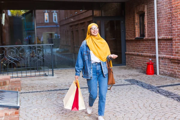 Концепция продажи и покупки - Счастливая арабская девочка с сумками для покупок после шопинга — стоковое фото