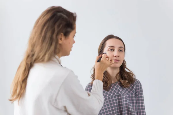 Beauty and cosmetics concept - Makeup artist doing professional make up of young woman