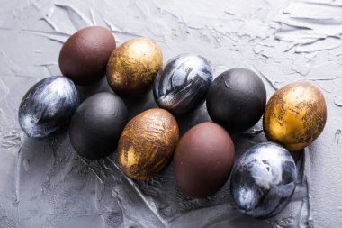 Tatiller, gelenekler ve Paskalya konsepti - Gri arka planda koyu renkli paskalya yumurtaları.