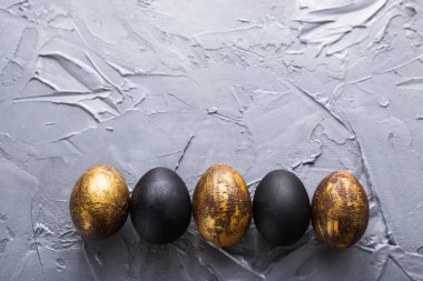 Tatiller, gelenekler ve Paskalya konsepti - Gri arka planda koyu renkli paskalya yumurtaları