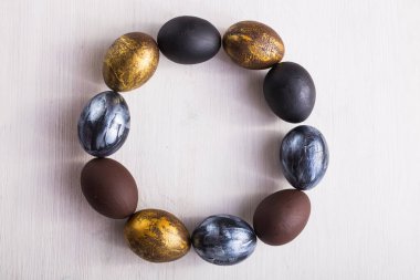 Tatiller, gelenekler ve Paskalya konsepti - Beyaz ahşap arka planda koyu renkli paskalya yumurtaları.