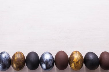 Tatiller, gelenekler ve Paskalya konsepti - Beyaz ahşap arka planda koyu renkli paskalya yumurtaları.