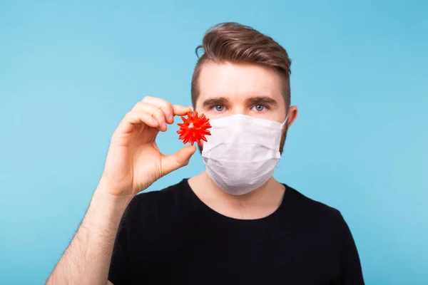 Covid-19, Ανάπτυξη εμβολίου και ιατρική έννοια - Man in flu mask and protective gloves holding a model of coronavirus. — Φωτογραφία Αρχείου