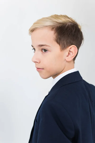 Portret van stijlvolle schooljongen tiener in wit shirt en jas tegen witte achtergrond. — Stockfoto