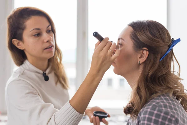 Skönhet och kosmetika koncept - Makeup artist gör professionell make up av ung kvinna — Stockfoto