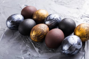 Tatiller, gelenekler ve Paskalya konsepti - Gri arka planda koyu renkli paskalya yumurtaları.