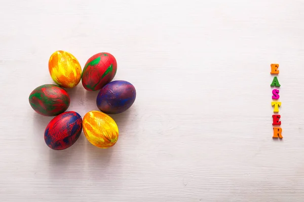 Wielokolorowe drewniane litery składające się na słowa szczęśliwy Wielkanoc i dekoracyjne kolorowe jaja na białym tle z miejsca do kopiowania. — Zdjęcie stockowe