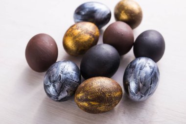 Tatiller, minimalizm, gelenekler ve Paskalya konsepti - Beyaz ahşap arka planda koyu renkli paskalya yumurtaları.