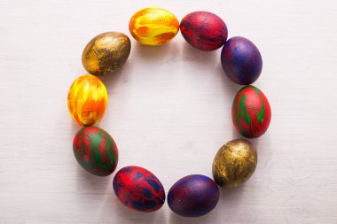 Tatiller, gelenekler ve Paskalya konsepti. Beyaz arka planda renkli renkli yumurtalar. Üst görünüm.