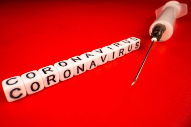 Pandemik ve virüs kavramı - Coronavirus metni ve kırmızı arka planda şırınga. Roman Coronavirus Covid-19.