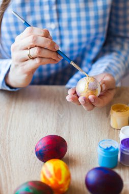 Tatiller, el yapımı ve yaratılış konsepti - Mutlu genç kadın Paskalya yumurtasına yakın plan çiziyor..