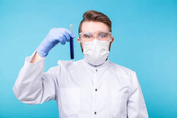 Covid-19, Vaccinutveckling, pandemi, utbrott och koronaviruskoncept - Man scientist in flu mask and protective gloves holding a test tube. — Stockfoto