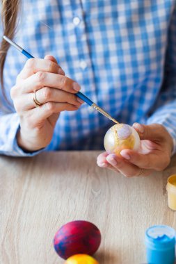 Tatiller, el yapımı ve yaratılış konsepti - Mutlu genç kadın Paskalya yumurtasına yakın plan çiziyor..