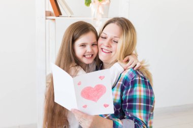 Anneler Günü ve aile tatilleri - Anne kızından tebrik kartı okuyor.