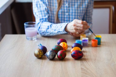 Tatiller, el yapımı ve yaratılış konsepti - Mutlu genç kadın Paskalya yumurtasına yakın plan çiziyor..