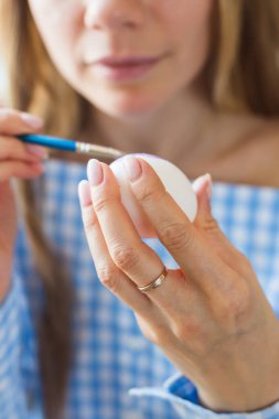 Tatiller, el yapımı ve yaratılış konsepti - Mutlu genç kadın Paskalya yumurtasına yakın plan çiziyor..